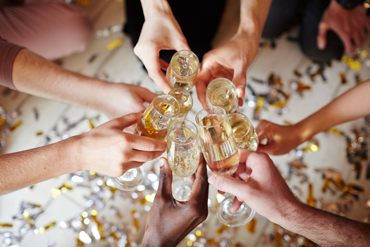 A group of friends toasting on top of a table full of confetti