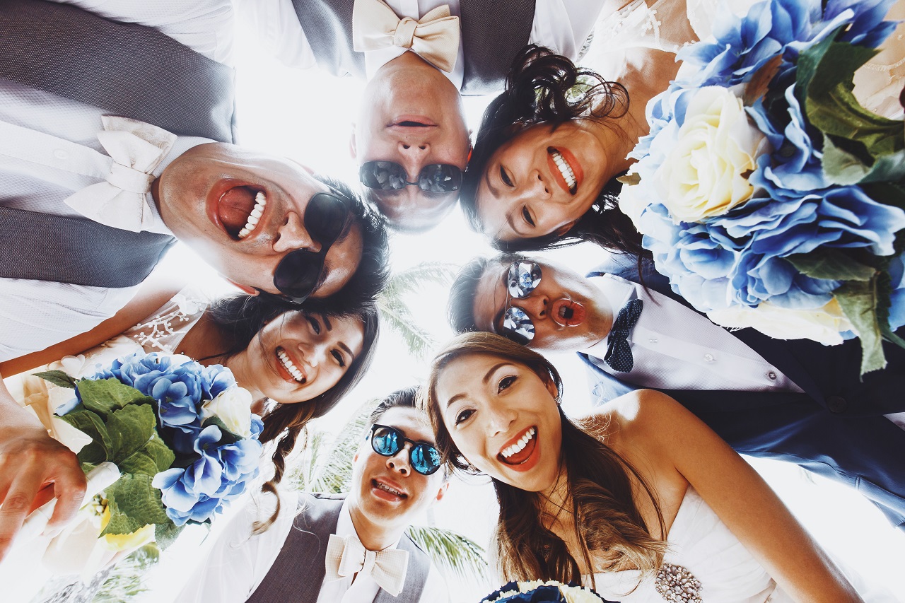 A wedding couple and their entourage looking down at the camera