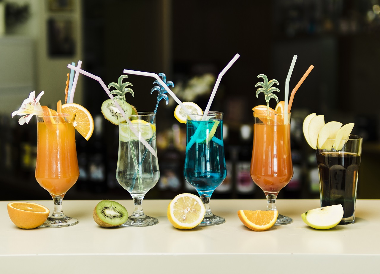 Five different types of cocktails with its respective fruit in front of it