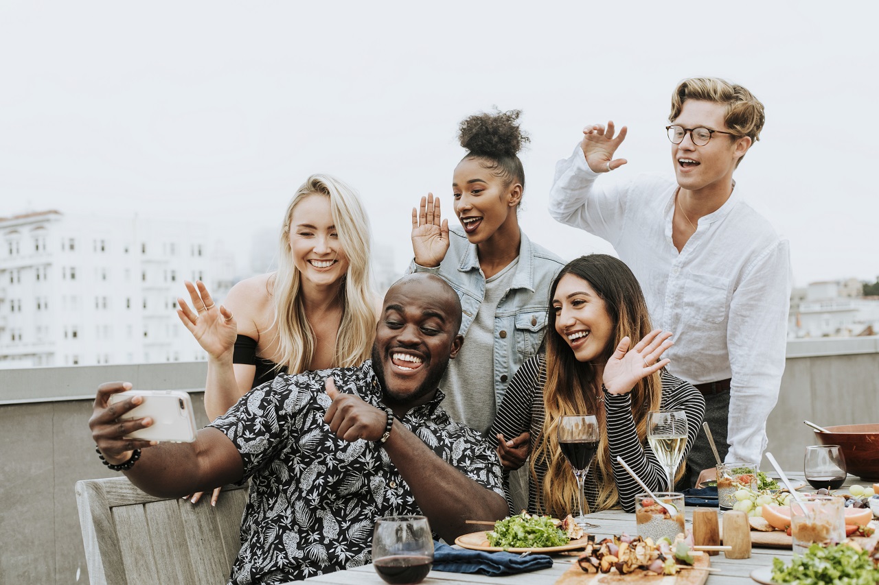 A group of friends taking a selfie at a rooftop party