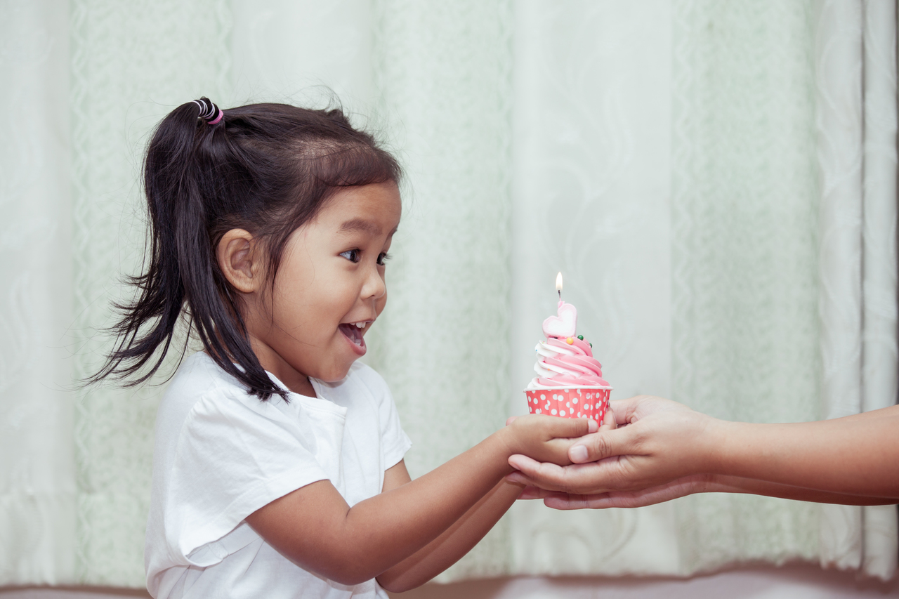 An little girl celebrating her birthday with a cupcake